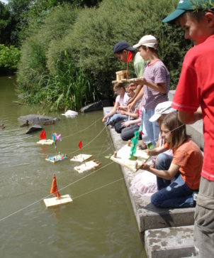 Kinder testen gebaute Boote auf dem Wasser
